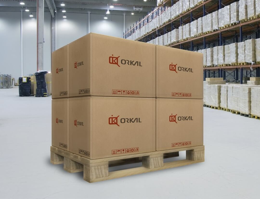 A stack of large cardboard boxes marked "orkal" on a wooden pallet in a warehouse with shelves stocked in the background.